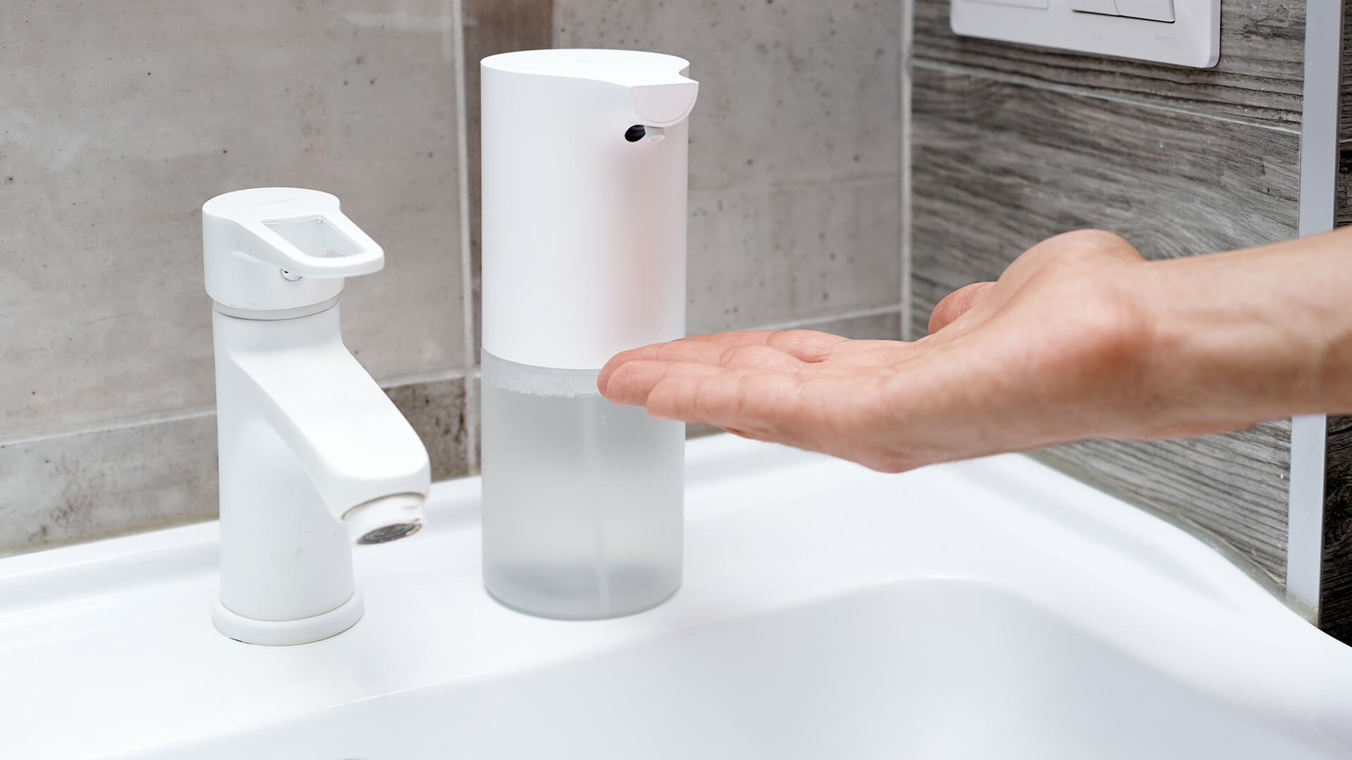 Man using contactless soap dispenser at home