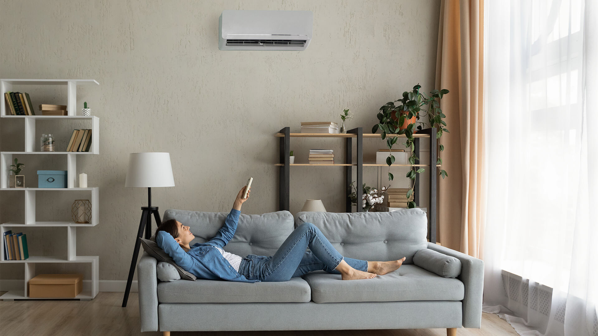 Woman at home on her sofa using a remote to control the HVAC system