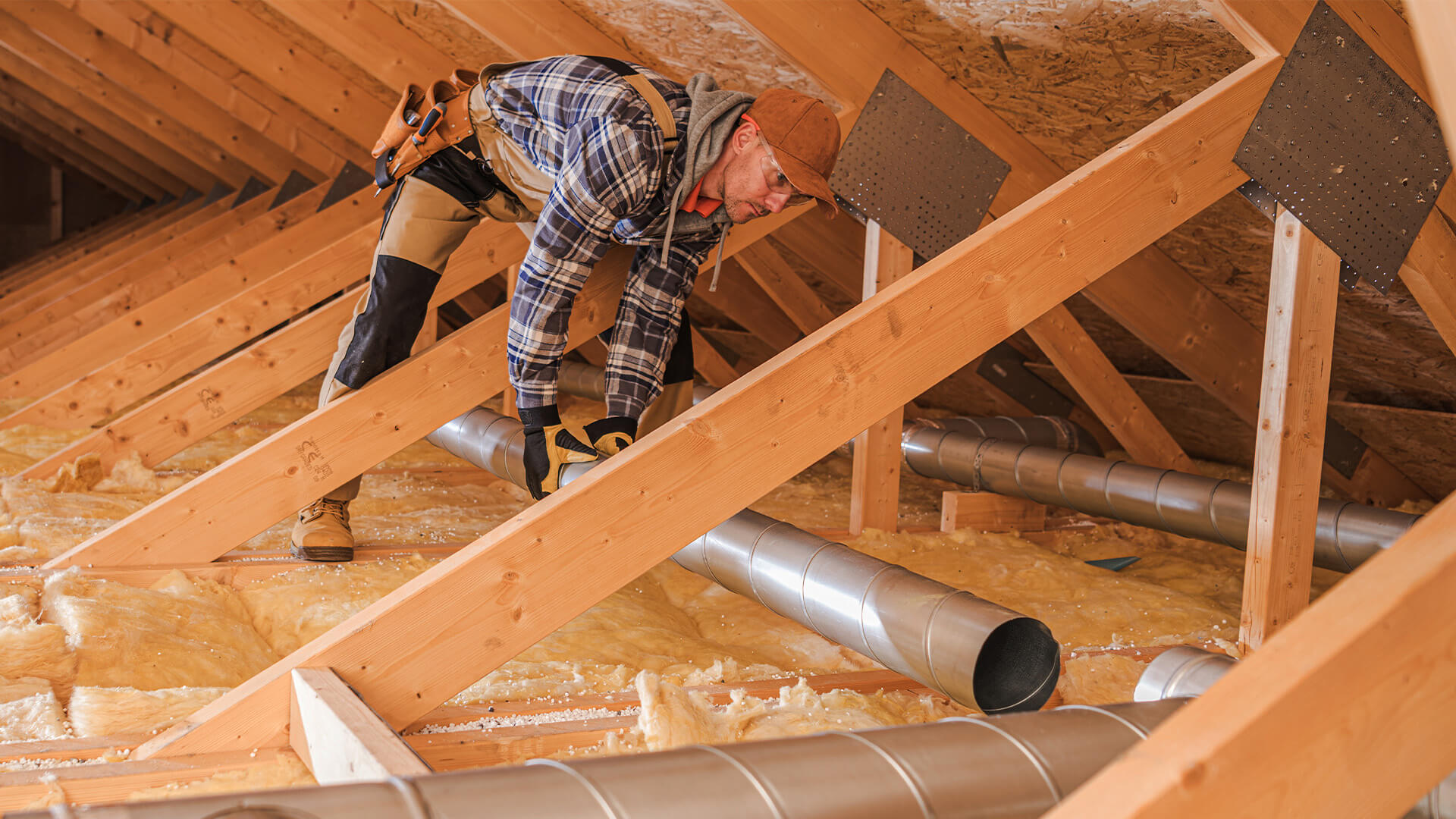 Man installing ventilation tubes in a home's attic