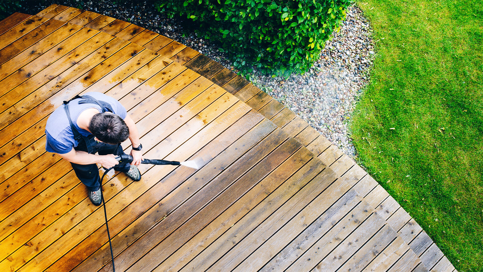 Man using a pressure washer on home interior decking