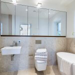 Luxury Modern Light Coloured Bathroom with a Large Mirror, sink, toilet and bath