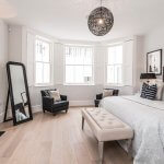 A wood theme luxury bedroom with a large standing mirror and chair