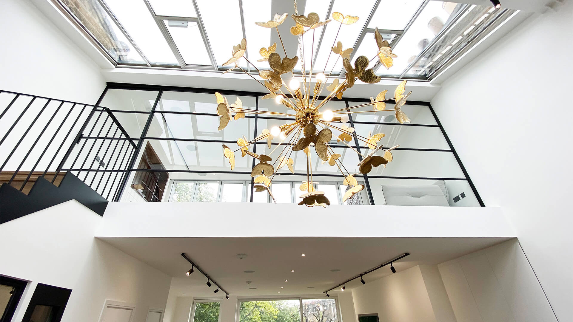 Gold Butterfly Chandelier hanging from a Luxury kitchen next to black stairs