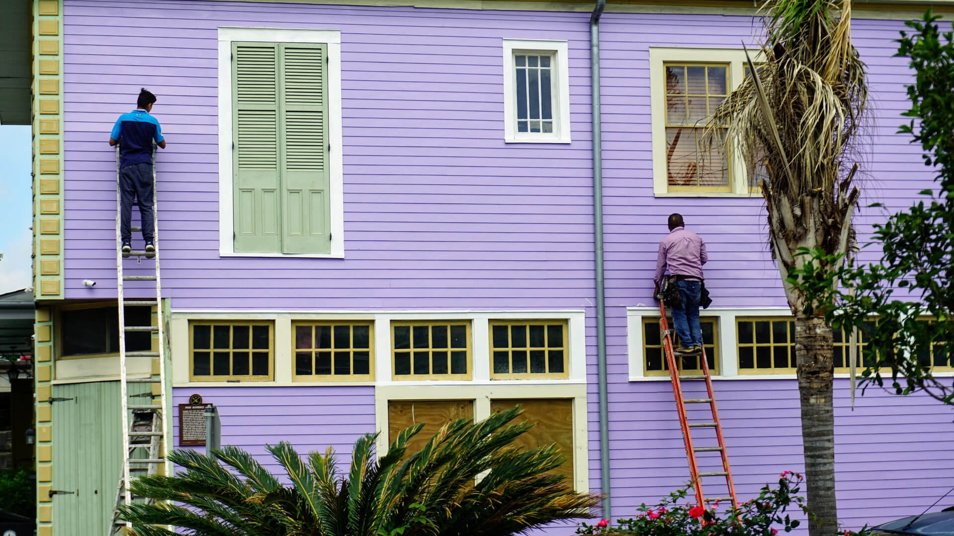 Painters painting wooden siding on a building pastel colours