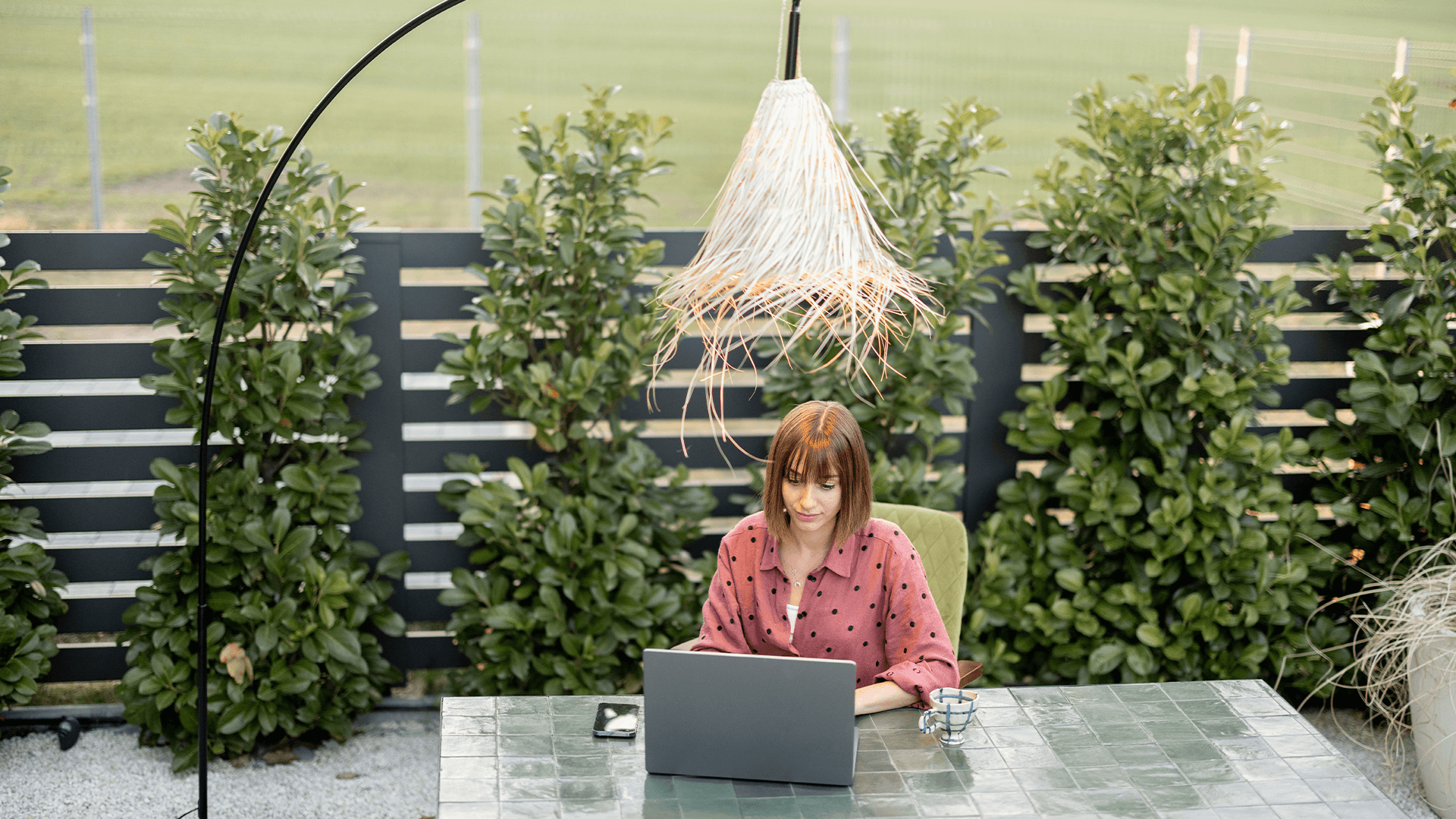 Young woman works on laptop at outdoor workspace in the garden