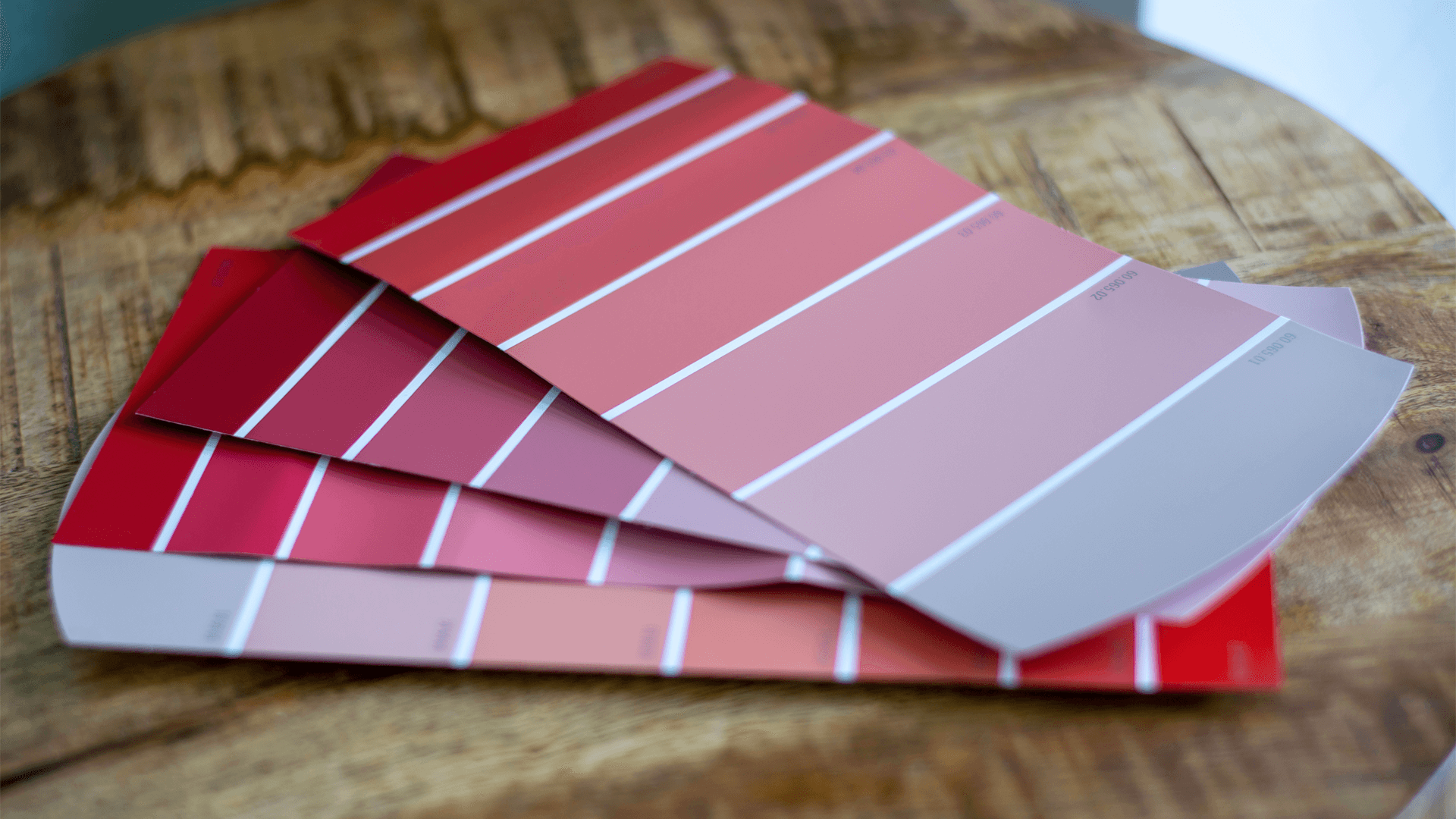 Pink colour swatches on wooden table, paint samples