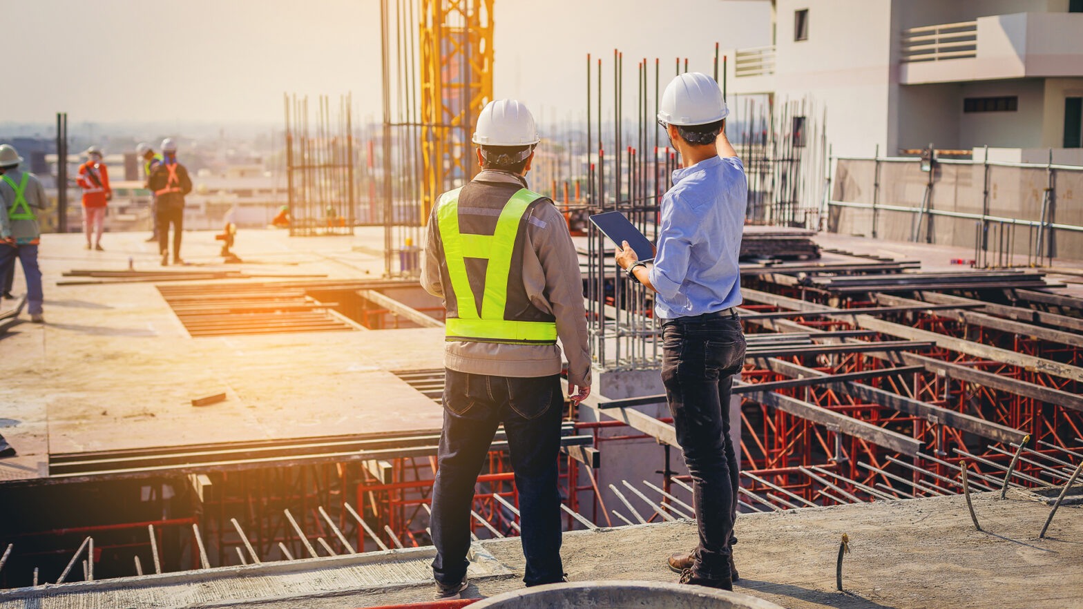 Structural engineer and foreman worker with touch pad discuss